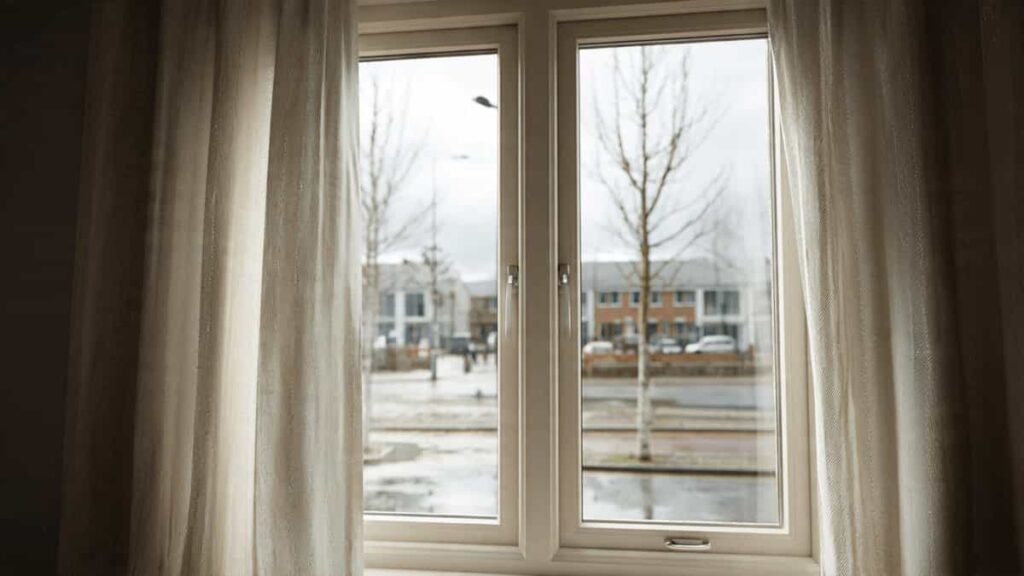 A cozy living room interior during a rainy UK winter, showcasing modern window frames that prevent condensation and heat loss.