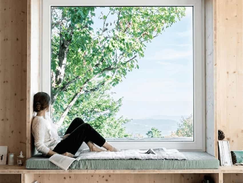 uPVC Double Glazed Windows Options Woman looking through a large fixed uPVC picture window at a mountain and forest landscape