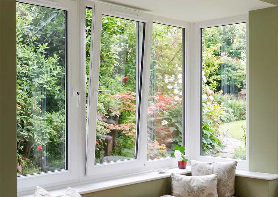 Interior view of an elegant bay window installation featuring modern uPVC tilt-and-turn windows and a custom window seat.